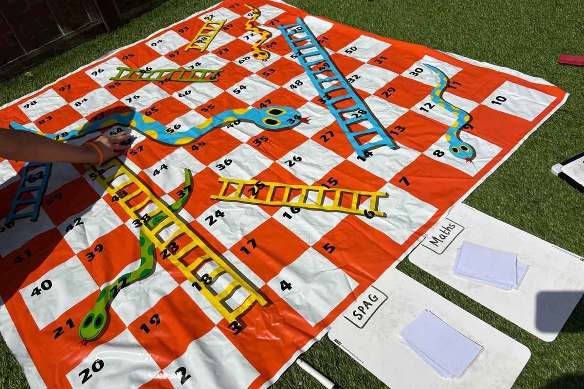 A giant snakes and ladders game with maths cards