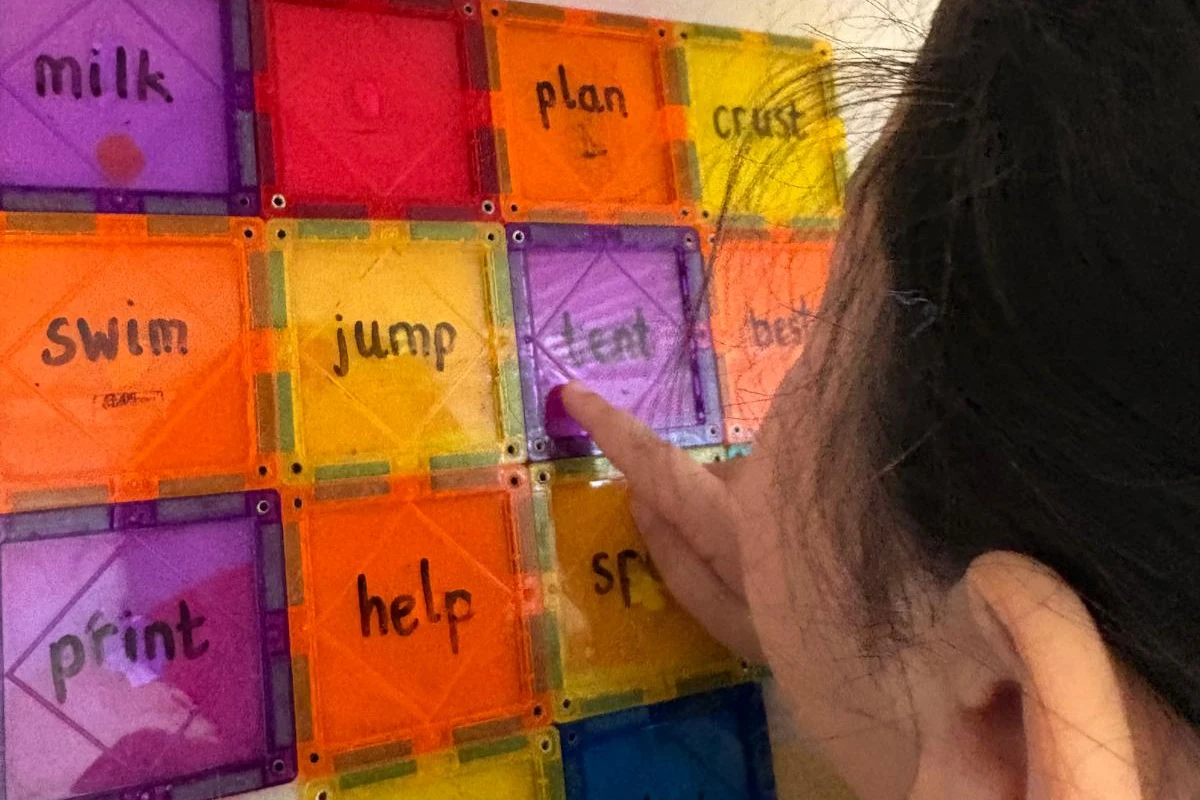 A child pointing at word tiles on a window