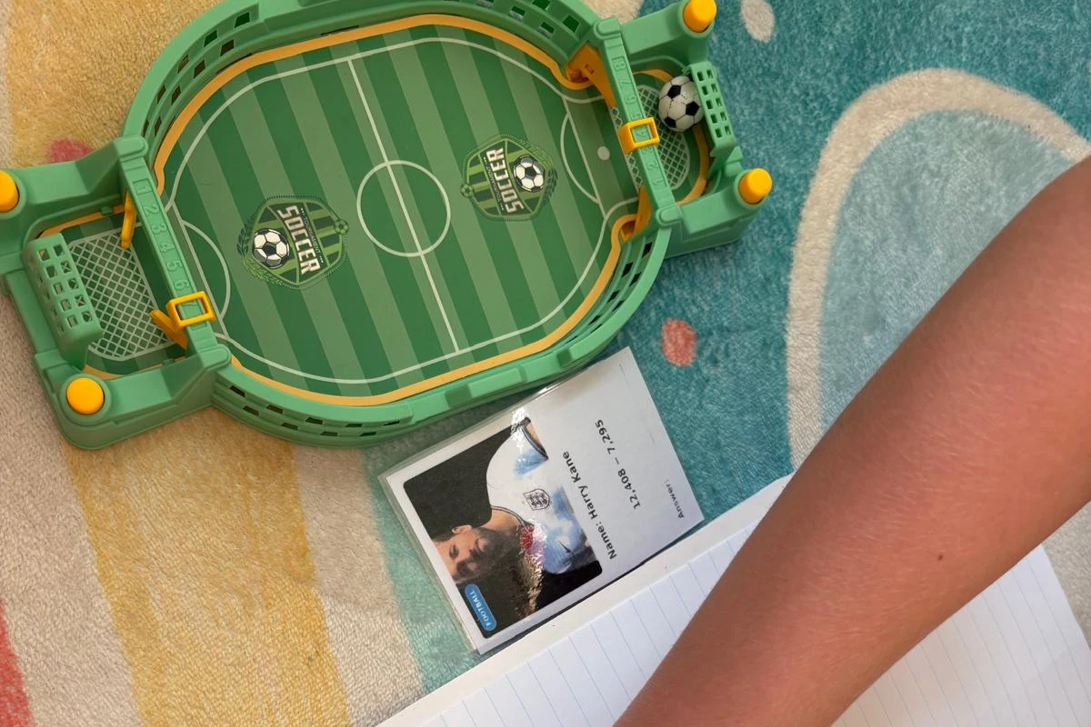 A child doing maths with a football game and player card